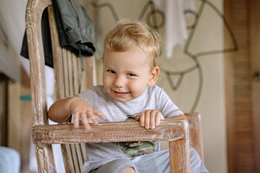 Charming young boy sitting on a chair with a playful expression indoors.